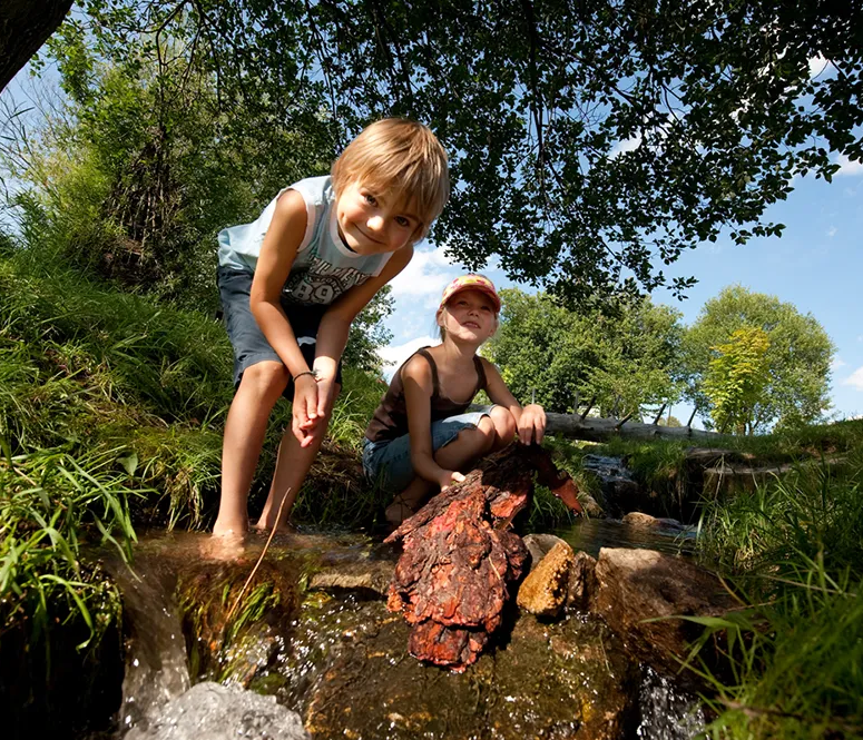 Kinder spielen am Bach