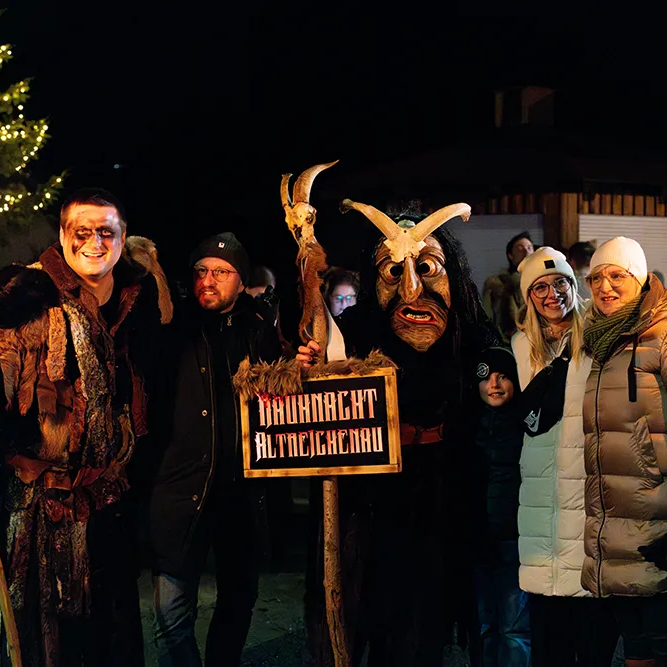 Die Teilnehmer der traditionellen Rauhnachtsfeier in Altreichenau stehen zusammen, einige tragen typische Lousnachtsmasken und Kostüme.