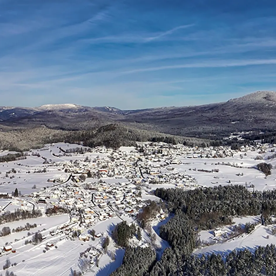Harmonische Winteransicht mit bepuderter Bergkette und schneebedeckten Wäldern und Lindberg im Herzen