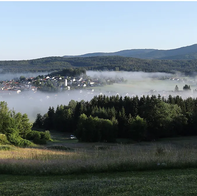 Panoramablick auf die Ortschaft Riedlhütte im Nebelschleier Eine malerische Landschaft mit sanften Hügeln und Nebelschwaden über der Ortschaft Riedlhütte.