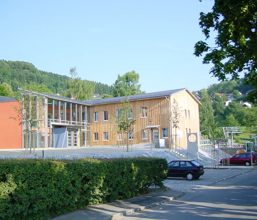 Die Architektur des KuK kombiniert Holz und Glas, eingebettet im grünen Markt Schönberg.
