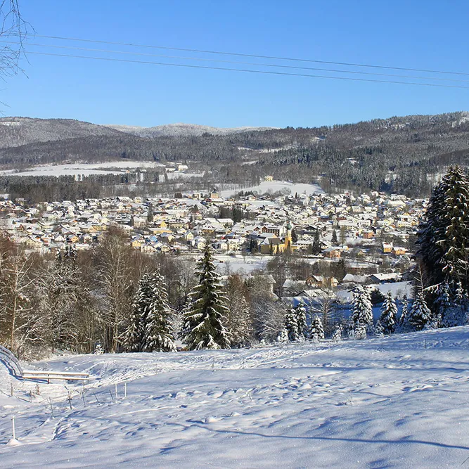 Winterlandschaft mit schneebedecktem Frauenau im Hintergrund