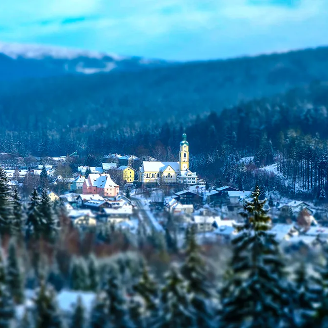 Märchenhafte Winteransicht auf den Grenzort Bayerisch Eisenstein Winterliches Bayerisch Eisenstein, das von hohen Fichtenwäldern umgeben ist, mit der Kirche im Mittelpunkt.