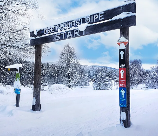 Das Schild markiert den Startpunkt der Dreikönigskloipe, während tiefer Schnee die Landschaft in eine friedliche Winteridylle verwandelt.