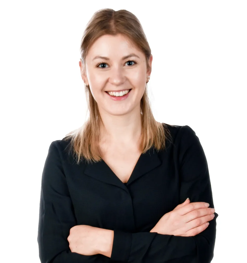 Die Mitarbeiterin Lisa Schuster aus der Verwaltung strahlt Freude aus, während sie in einem schwarzen Oberteil gekleidet ist.