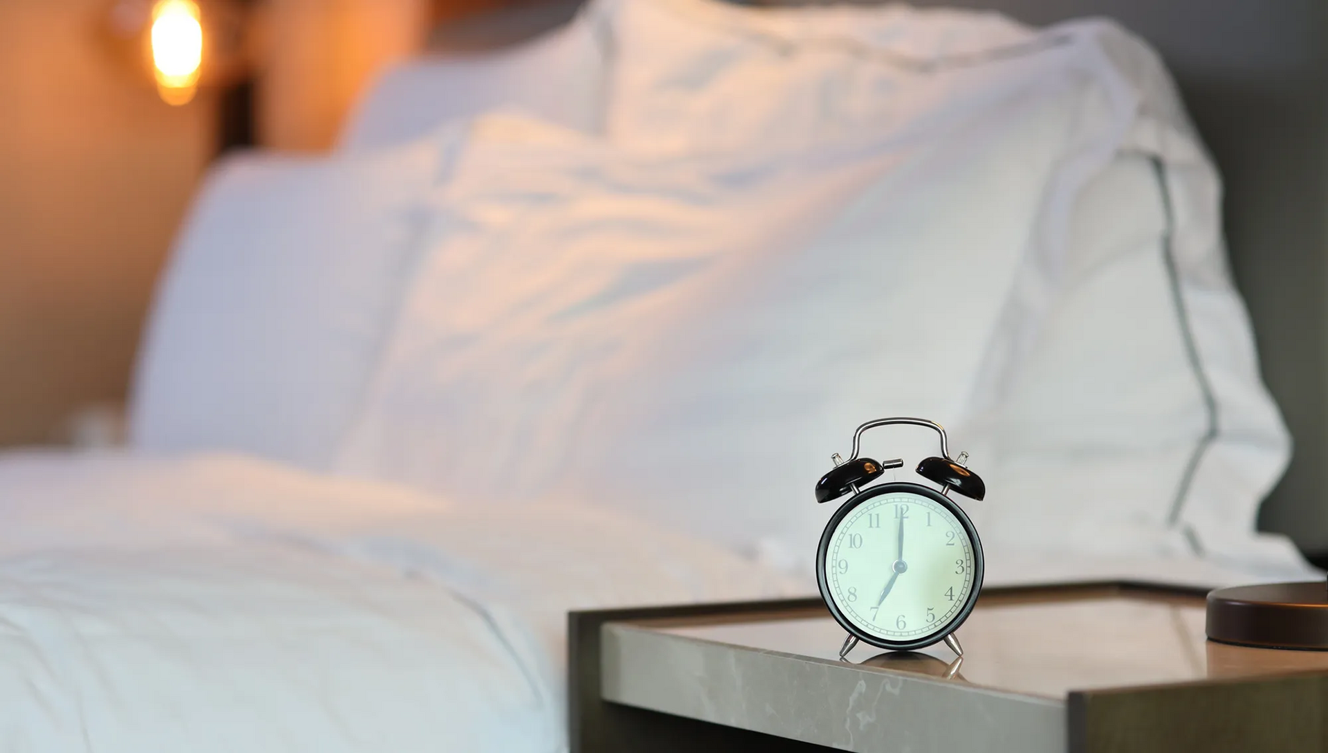 Bett mit Wecker im Vordergrund