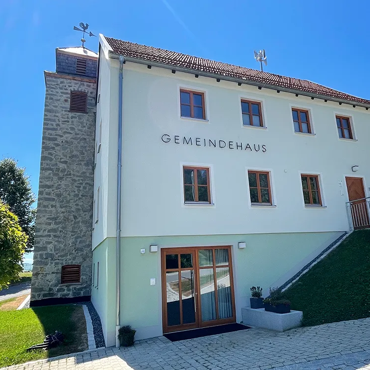 Das Gemeindehaus in der Ferienregionsgemeinde Eppenschlag, umgeben von Bäumen und einem gepflegten Garten, strahlt Ruhe und Gemeinschaftsgefühl aus.